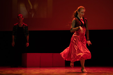 Dancer in a red dress dancing Spanish flamenco on the stage in the theater