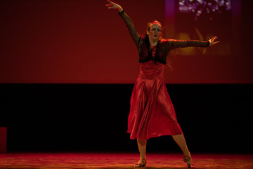 Dancer in a red dress dancing Spanish flamenco on the stage in the theater