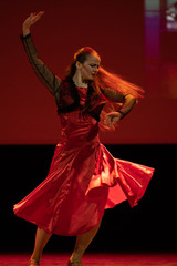 Dancer in a red dress dancing Spanish flamenco on the stage in the theater