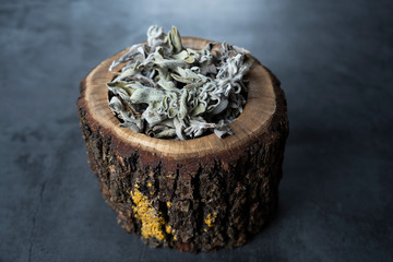 Dry sage, salvia tea in wooden bowl on concrete, stone background. Organic, healthy and relaxing herbals.