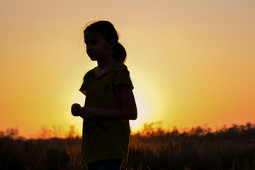 Fototapeta premium Silhouette of a girl on a background of sunset in the field.