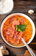 1  plate of russian soup,  red borscht with parsley and  sour cream , garlic, bread, spoon, top view,