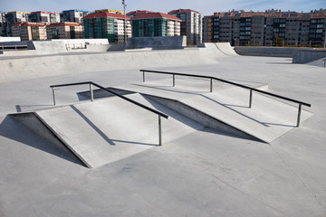 Sloped metal rails for grind tricks in an empty concrete skatepark - obrazy, fototapety, plakaty