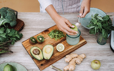 Young woman preparing detox juice with cold pressed extractor machine - Girl making smoothie with...