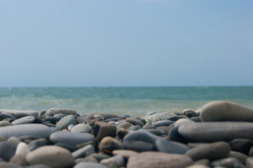 Fototapeta na wymiar Beach. View of the sea and smooth horizon from the pebble beach. In the foreground are large pebble stones. It's a focus. Background for blog or site, photowallpaper for computer.