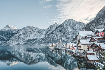 Snowy village Hallstatt by lake at foot of snow mountain with clear sky in winter in Austria