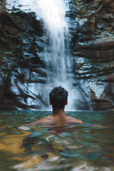 man in the water in front of waterfall 