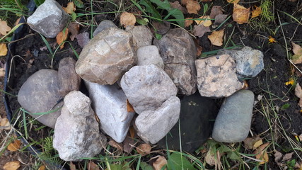 A pile of gray stones lie on the grass for the background, abstract