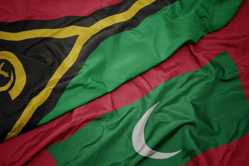 waving colorful flag of maldives and national flag of Vanuatu .