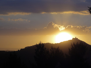 Włochy, Toskania - Słońce zachodzące za wzgórzem ze starym średniowiecznym zamkiem