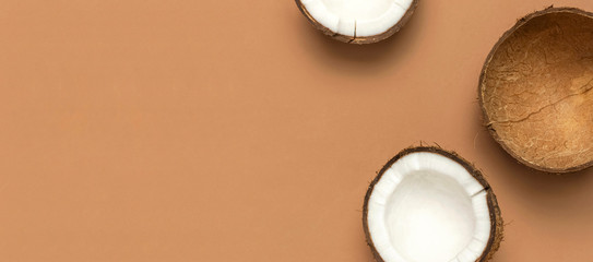 Creative layout with coconuts. Whole and half coconut on brown background. Minimal flat lay style, top view copy space. Food concept. Tropical exotic fruit, summer golden background