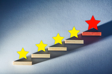 Customer experience. Service rating. Yellow and red stars on wooden staircase on blue background....