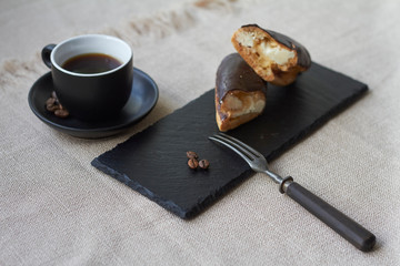 Pastry filled with cream, traditional french eclairs with chocolate and cup of espresso, selective...