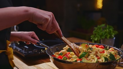 Woman cooking frying in kitchen in wok pan