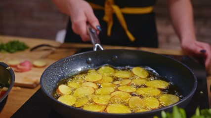 Woman cooking frying in kitchen in wok pan