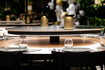 A dinner in a restaurant for a birthday party. A table set with cutlery and glasses and decorations of white balloons in the background.