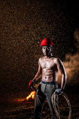 Fototapeta na wymiar Asian muscular man black hair and bread serious face topless cross rescue rope on torso and holding fire axes in right hand standing in dark fire smoke and pouring rain background 