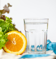 salade leaf. orange, cup of water and measuring blue tape on white background , healthy lifestyle and drinking water concept