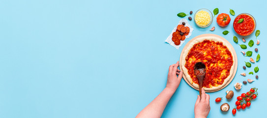 Putting pizza sauce on the dough with a wooden spatula