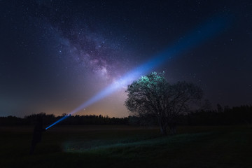 Low angle view of person illuminating the night sky and the milky way/galactic core with torch