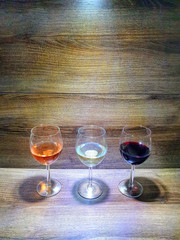 Three glasses of wine on a wooden texture background. rose wine, white wine, red wine