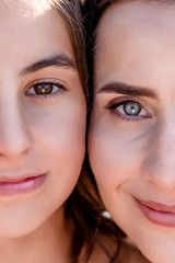 Portrait of young attractive short-haired smiling mother and her little cute daughter with big brown and blue eyes and red natural lips.Face to face.Happy family.Lovely mothers day.