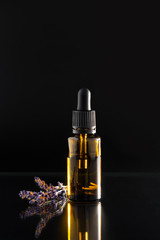 Aromatherapy essential oil dropper bottle and lavender herb flower leaf , black background.