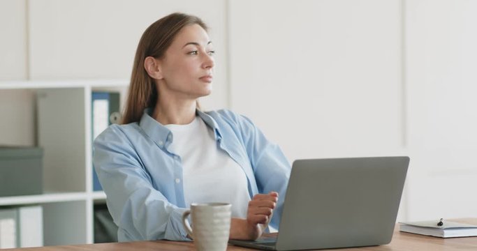 Woman massaging her neck, working remotely on laptop