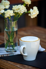 Cappucino in restaurant and flowers