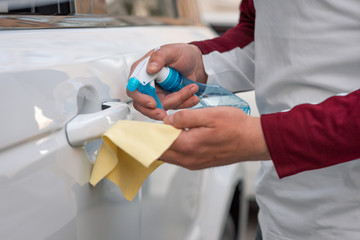 Hand of man is spraying alcohol,disinfectant spray on handle of car door,safety,prevent infection...