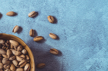 Pistachios. Pistachio nuts in a brown bowl on a concrete background. Healthy eating concept.