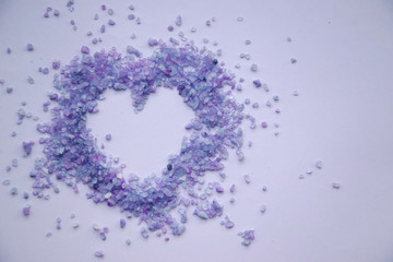 Close up picture of violet heart on light lavender background. Decorative sea salt with purple shade. Small crystals of salt. Top view, copy space concept. Greeting card on valentine,wedding, engagemt