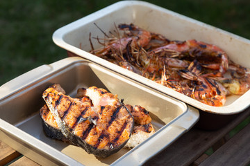 grilled langoustines and salmon steaks in pots. outdoor BBQ. Summer time