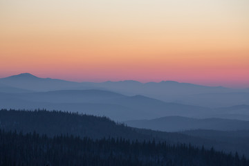 Beautiful smoky sunset in the mountains. The sun sets over the horizon
