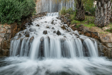 Fototapeta na wymiar Long exposure artificial waterfall with stones