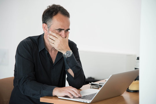 uomo con occhiali di vasti &egrave; seduto e impegnato a lavoro