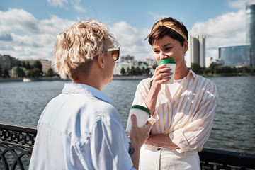 Two women walking outdoor with coffee