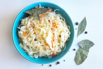 Fermented foods. Homemade sauerkraut in a blue bowl, on a white background. Top view, close-up, selective focus
