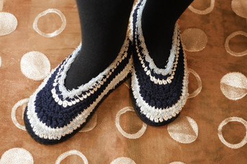Homemade knitted slippers on the feet of a woman, in such slippers in the winter at home warm and cool in the summer