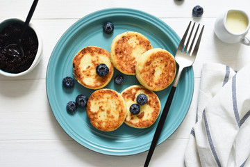 Cheese pancakes with jam and blueberries on the kitchen table. Good morning!