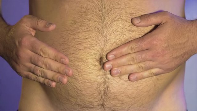 Man slaps his hands against his hairy fat belly and waves of subcutaneous fat spread out slow motion. Concept of healthy food and lifestyle. Human body without clothes