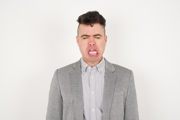 Negative human expressions and attitude. Angry dissatisfied male has disgusting expression as sees something not appealing, frowns face, isolated over white  background. Distaste and dislike