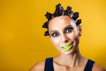 girl on a yellow background with an original creative afro hairstyle in the form of horns, smiling...