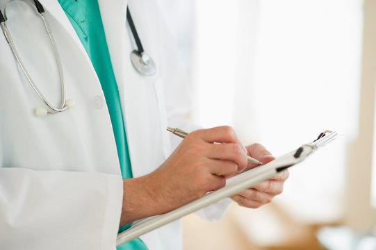 Male doctor writing medical report