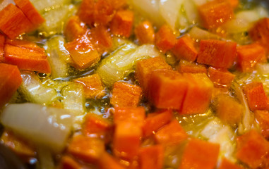 Frying finely chopped carrots and onions in boiling oil, close-up