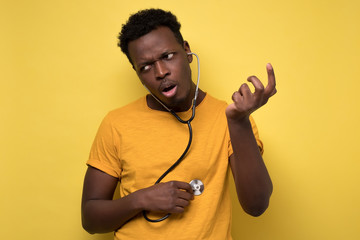 african american man applying stethoscope to himself listening to his heart.