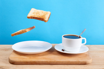 Fresh traditional breakfast with crispy toasts and cup coffee or tea on blue background. Levitation food concept.