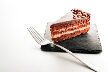 a piece of chocolate cake with a fork on a black stone. the view from the top.the concept menu