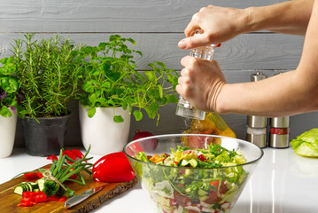 salad from fresh vegetables in a plate on a table. bowl of salad with vegetables and greens on white table. Women preparing vegetable salad- close up shot. Domestic kitchen. Vegetarian food. spices in