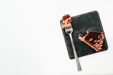 a piece of chocolate cake with a fork on a black stone. the view from the top.the concept menu